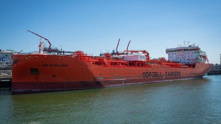 A large red oil tanker named Bow Excellence docked at a harbor under clear blue skies.